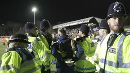 Seorang fans ditahan Polisi setempat setelah berlari memasuki lapangan saat putaran kelima Piala FA antara Arsenal melawan Sutton United di Gander Green Lane stadium, London, (20/2/2017). Arsenal menang 2-0. (AP/Matt Dunham)