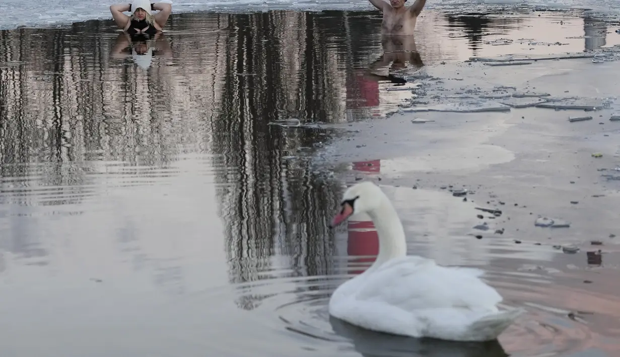 Orang-orang berenang di danau dengan suhu di bawah titik beku di Warsawa, Polandia (26/12/2021). Iklim di Polandia pada musim dingin yang sangat dingin, seringkali di bawah titik beku (0 °C atau 32 °F), dan musim panas yang hangat.  (AP Photo/Czarek Sokolowski)