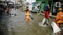Petugas PPSU membersihkan sampah saat terjadi banjir rob di Pelabuhan Kali Adem, Muara Angke, Jakarta, Selasa (9/11/2021). Walau terendam banjir rob, petugas PPSU tetap sigap bersihkan sampah yang mengambang terbawa air laut. (Liputan6.com/Faizal Fanani)