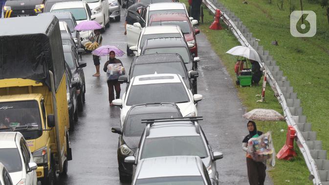 Sejumlah pedagang asongan menawarkan dagangan kepada pengendara di jalan tol Jagorawi yang sedang menanti waktu buka tutup jalur menuju kawasan wisata puncak, Bogor, Jawa Barat, Sabtu (31/10/2020). (Liputan6.com/Helmi Fithriansyah)