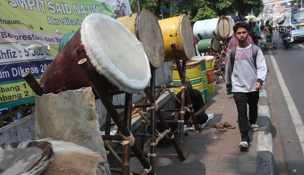 Seorang pria melintas di depan bedug di Jalan KH Mas Mansyur, Tanah Abang, Jakarta, Kamis (31/5). Memasuki pertengahan bulan Ramadan, penjualan bedug mengalami peningkatan. (Liputan6.com/Arya Manggala)