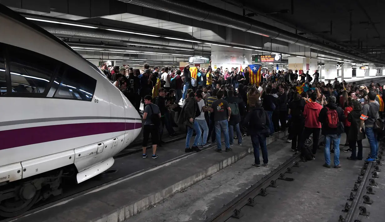 Ratusan massa pro-kemerdekaan Catalonia saat memblokir rel kereta api di Stasiun Sants di Barcelona (8/11). Pengunjuk rasa memblokir jalan dan jalur kereta api setelah para pemimpin separatis ditahan di Madrid. (AFP Photo/Lluis Gene)