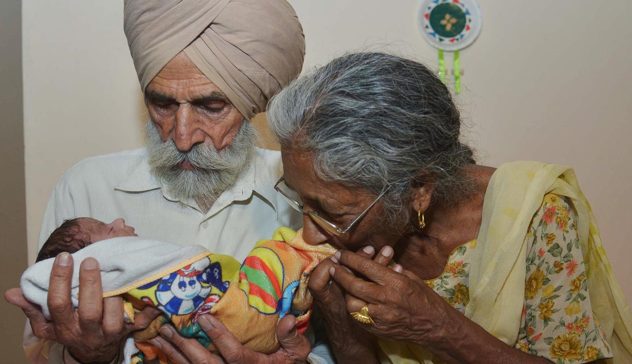 Pasangan Daljinder Kaur (kiri) bersama sang suami Mohinder Singh Gill saat menggendong bayi kesayangan mereka di Amritsar, India, Rabu (11/5).Nenek berusia 70 tahun ini berhasil melahirkan seorang bayi laki-laki bernama Armaan.( NARINDER NANU / AFP)
