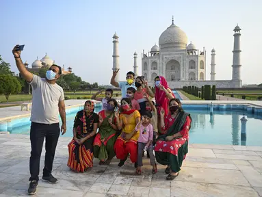 Sekelompok wisatawan berfoto dengan latar belakang Taj Mahal setelah dibuka kembali untuk pengunjung di Agra, Rabu (16/6/2021). Taj Mahal, yang terkenal sebagai ikonik India telah dibuka kembali untuk umum, ketika negara itu mulai melonggarkan pembatasan Covid-19. (Money SHARMA/AFP)