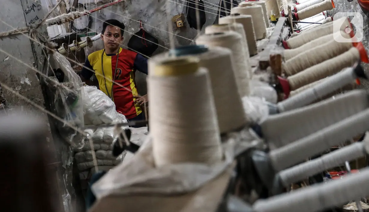 Pekerja memintal benang di Kebayoran, Jakarta, Selasa (5/7/2022). Pabrik benang yang berdiri sejak tahun 1970-an tersebut dapat memproduksi 100 kilogram benang dalam sehari dan dipasarkan ke berbagai daerah di Indonesia. (Liputan6.com/Johan Tallo)