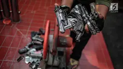 Petugas memperlihatkan barang bukti senjata api sebelum pemusnahan di Kejaksaan Negeri Jakarta Barat, Selasa (11/12). Pemusnahan barang bukti merupakan bentuk keseriusan penegak hukum dalam pengentasan kasus-kasus kejahatan. (Liputan6.com/Faizal Fanani)