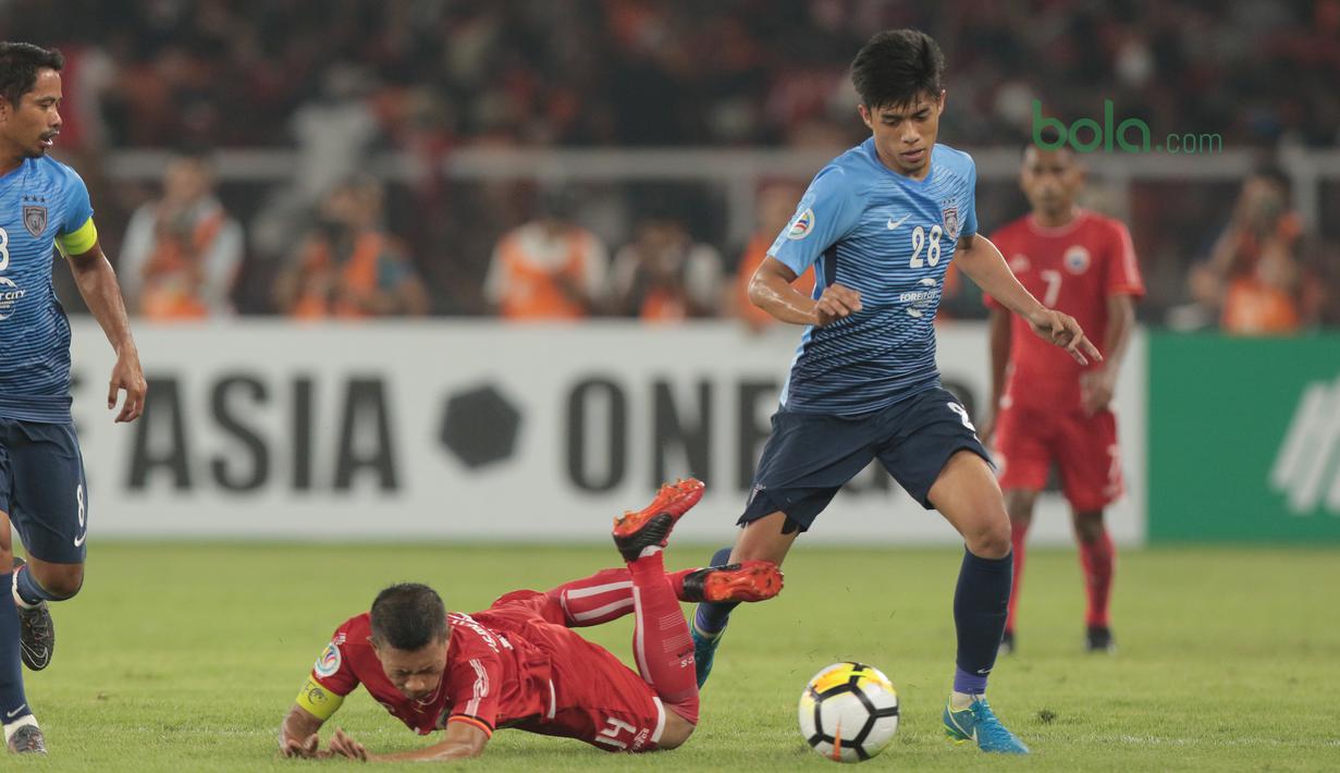 Pemain Persija Jakarta, Ismed Sofyan jatuh saat berebut bola dengan dua pemain JDT pada laga Piala AFC 2018 di Stadion Utama Gelora Bung Karno, Jakarta, Selasa (10/4/2018). Persija Jakarta menang 4-0.  (Bola.com/Nick Hanoatubun)