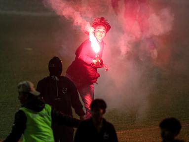 Seorang suporter menyalakan flare di dalam lapangan saat berlangsungnya laga leg kedua final Pegadaian Liga 2 2023/2024 antara Semen Padang mengadapi PSBS Biak di Stadion GOR Haji Agus Salim, Padang, Sabtu (9/3/2024). (Bola.com/Bagaskara Lazuardi)