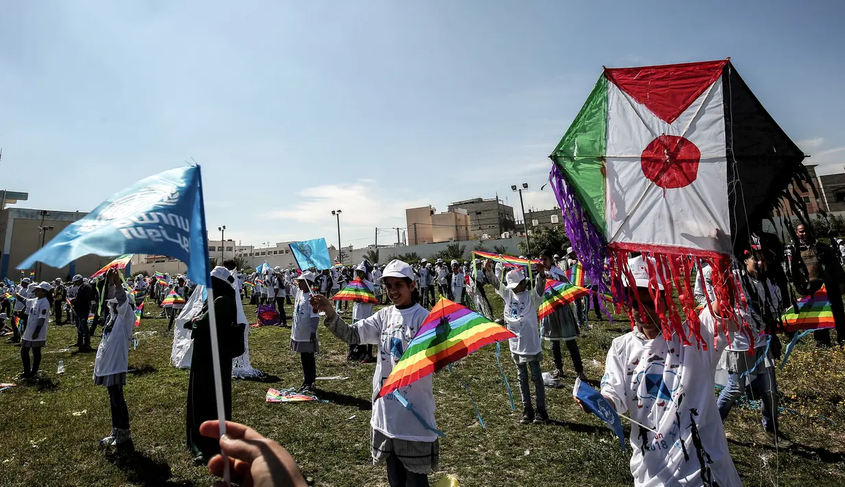 Anak-anak sekolah Palestina menerbangkan layangan berbendera Palestina dan Jepang dalam aksi solidaritas peringatan tujuh tahun gempa dan tsunami Jepang di Gaza, Selasa (13/3). (SAID KHATIB/AFP)