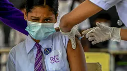 Seorang gadis sekolah bereaksi ketika seorang petugas kesehatan menyuntiknya dengan dosis vaksin Pfizer-BioNTech terhadap virus corona Covid-19 untuk kelompok usia 12-15 tahun di sebuah lembaga pendidikan di Kolombo, Sri Lanka (7/1/2022). (AFP/Ishara S. Kodikara)