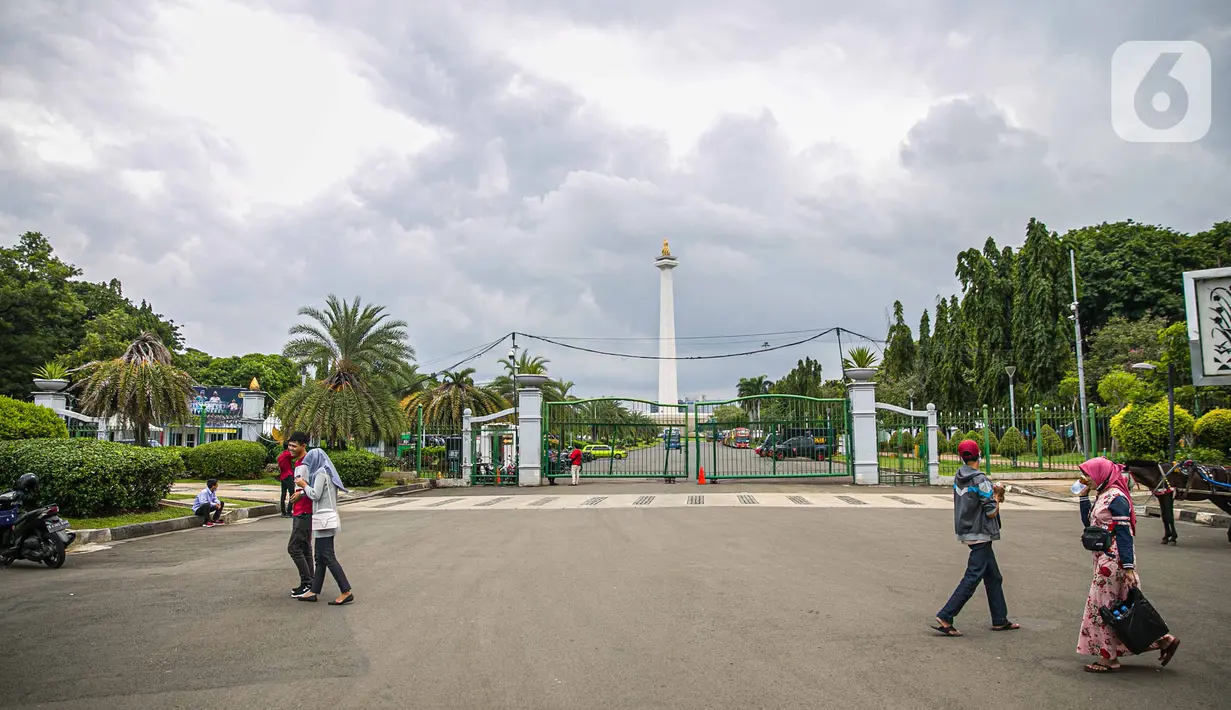 Warga berjalan di kawasan Monumen Nasional atau Monas di Jakarta, Jumat (1/1/2021). Pemerintah Provinsi DKI Jakarta menutup sejumlah tempat wisata selama masa libur Tahun Baru dari 25 dan 31 Desember 2020, serta 1 Januari 2021. (Liputan6.com/Faizal Fanani)