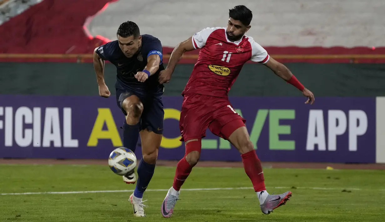 Pemain Al-Nassr, Cristiano Ronaldo (kiri) mengontrol bola dibayangi pemain Persepolis, Danial Esmaeilifar pada laga Grup E Liga Champions Asia 2023/2024 di Azadi stadium, Teheran, Iran, 19 September 2023. (AP Photo/Vahid Salemi)