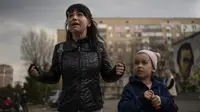 Julia, 34, menangis di samping putrinya Veronika, 6, saat berbicara dengan sekelompok wartawan di Brovary, di pinggiran Kyiv, Ukraina, Selasa, 29 Maret 2022. Invasi Rusia ke Ukraina yang dimulai pada 24 Feberuari 2022 masih berlangsung hingga hari ini. (AP Photo/Rodrigo Abd)