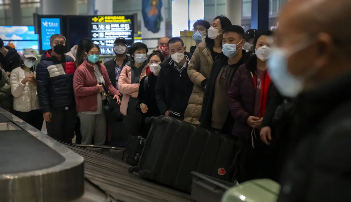 Pelancong yang memakai masker menunggu barang bawaan mereka di area kedatangan internasional di Bandara Internasional Ibukota Beijing di Beijing, Senin (9/1/2023). Pelancong internasional pertama tiba di China tanpa karantina wajib yang telah diberlakukan pada awal penerbangan. Pandemi tiga tahun lalu setelah pembatasan dicabut mulai hari Minggu. (AP/Mark Schiefelbein)