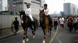 Dua pengunjung berkeliling area car free day  dengan menunggang kuda milik satuan polisi berkuda Polda Metro Jaya di Bundaran HI, Jakarta, Minggu (18/3). Kuda-kuda yang diterjunkan itu menarik perhatian pengunjung. (Liputan6.com/Faizal Fanani)