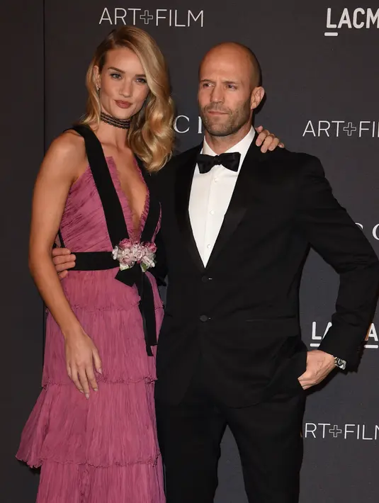 Model dan aktris Rosie Huntington -Whiteley berpose bersama sang kekasih, aktor Jason Statham saat menghadiri gala LACMA Art + Film di Los Angeles, California, Minggu (7/11). (AFP Photo/ Mark Ralston)