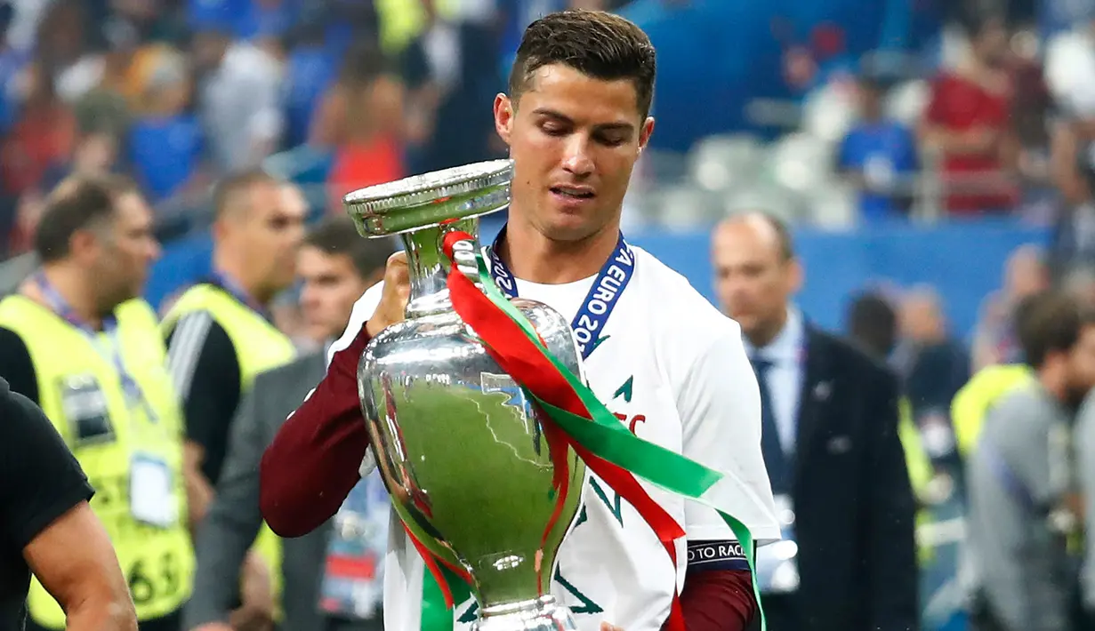 Cristiano Ronaldo membawa tropi Piala Eropa 2016 usai mengalahkan Prancis 1-0 di Stade de France, Senin (11/7). Ronaldo melesakkan gol paling banyak di EURO 2016 sebanyak 29 gol. Gol tersebut dihitung sejak babak kualifikasi. (REUTERS)