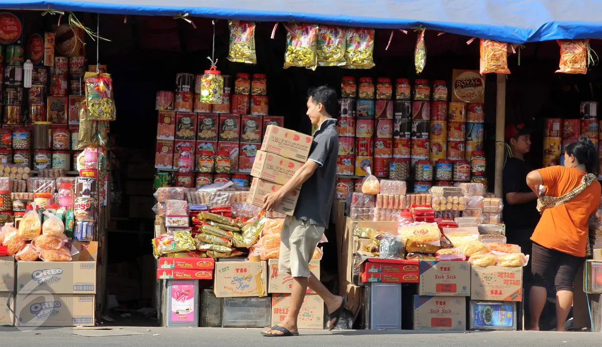 Warga berjalan di depan kios penjual kue kering musiman di kawasan Ciracas, Jakarta, Minggu (12/7/2015). Sejak beberapa hari terakhir, transaksi pedagang musiman kue kering mengalami peningkatan menjelang hari raya Idul Fitri. (Liputan6.com/Helmi Afandi)