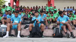 Pemain Malut United berbaur dengan anak-anak saat bersiap untuk coaching clinic di Stadion Marimoi, Tidore, Selasa (15/8/2023) sore WIB. (Bola.com/Okie Prabhowo)