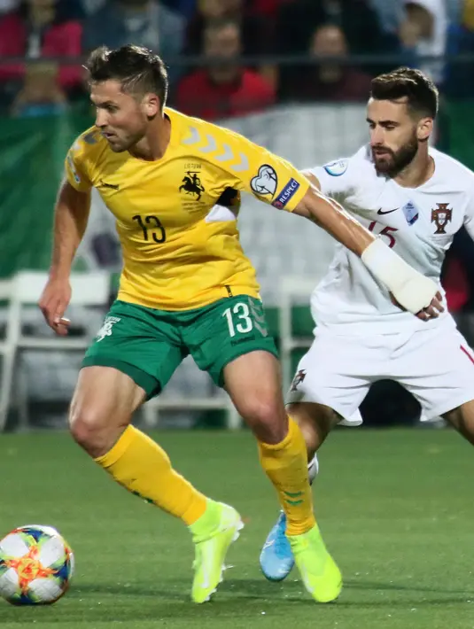 Pemain Lithuania, Saulius Mikoliunas menggiring bola dari kawalan Pemain Portugal, Rafa Silva selama pertandingan grup B Kualifikasi Euro 2020 di stadion LFF di Vilnius (10/9/2019). Portugal menang telak atas Lithuania 5-1. (AFP Photo/Petras Malukas)