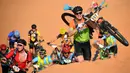 Para pebalap memanggul sepeda mereka menaiki gundukan pasir pada etape 1 edisi ke 14 balap sepeda gunung Titan Gurun 2019 di sekitar Kota Merzouga, Maroko, Minggu (28/4/2019). Trek Titan Gurun 2019 sepanjang 640 km menghubungkan antara Merzouga dan Maadid. (Franck Fife / AFP)