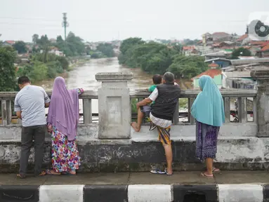 Sejumlah warga mengamati banjir yang menggenangi kawasan Rawajati dari atas flyover di Jakarta Timur, Rabu (1/1/2020). Banjir yang berasal dari luapan Sungai Ciliwung itu menjadi daya tarik tersendiri bagi sebagian pemotor yang melintasi di flyover tersebut. (Liputan6.com/Immanuel Antonius)