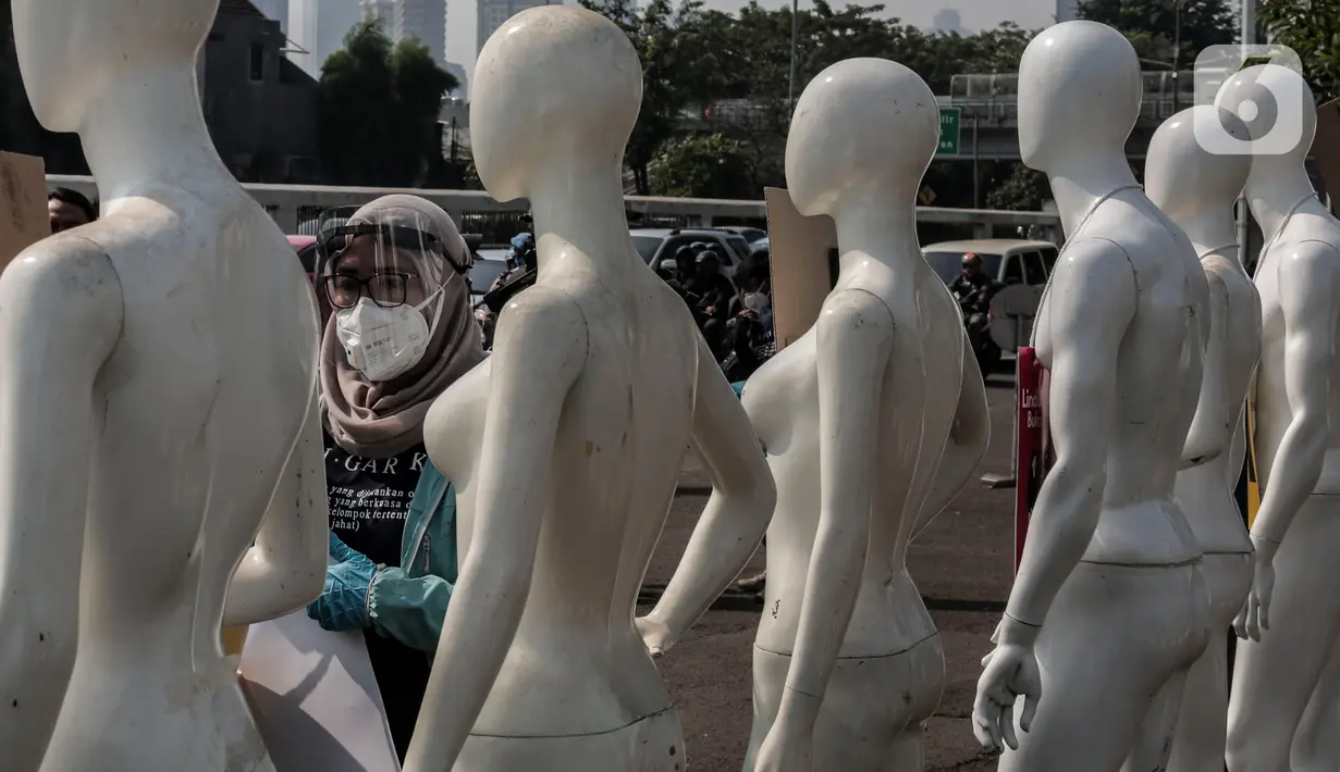 Aktivis Greenpeace Indonesia memasang poster pada puluhan maneken saat menggelar aksi damai di depan gerbang kompleks DPR, Jakarta Pusat, Senin (29/6/2020). Aksi tersebut dilakukan sebagai bentuk penolakan terhadap RUU Omnibus Law. (Liputan6.com/Johan Tallo)