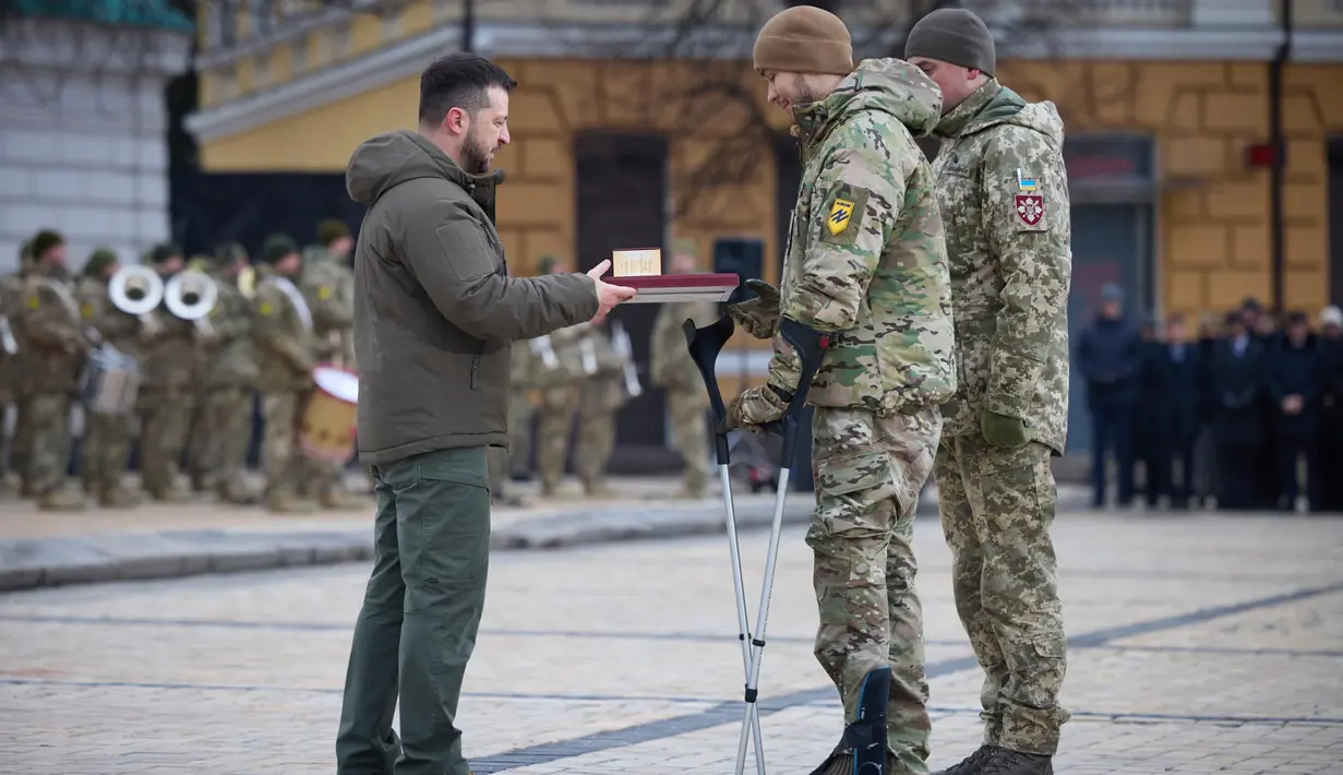 Presiden Ukraina Volodymyr Zelenskyy (kiri) memberikan penghargaan negara kepada seorang perwira dengan gelar Pahlawan Ukraina dalam acara peringatan satu tahun perang Rusia-Ukraina di Kyiv, Ukraina, Jumat, 24 Februari 2023. Volodymyr Zelenskyy mengenang teror yang dilancarkan setahun lalu oleh serangan Rusia, memicu perang terbesar dan paling banyak menelan korban tewas di Eropa sejak Perang Dunia II. (Kantor Pers Kepresidenan Ukraina via AP)