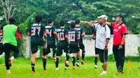 Abdurrahman Gurning (bertopi merah) saat melatih Arema Indonesia. (Bola.com/Iwan Setiawan)