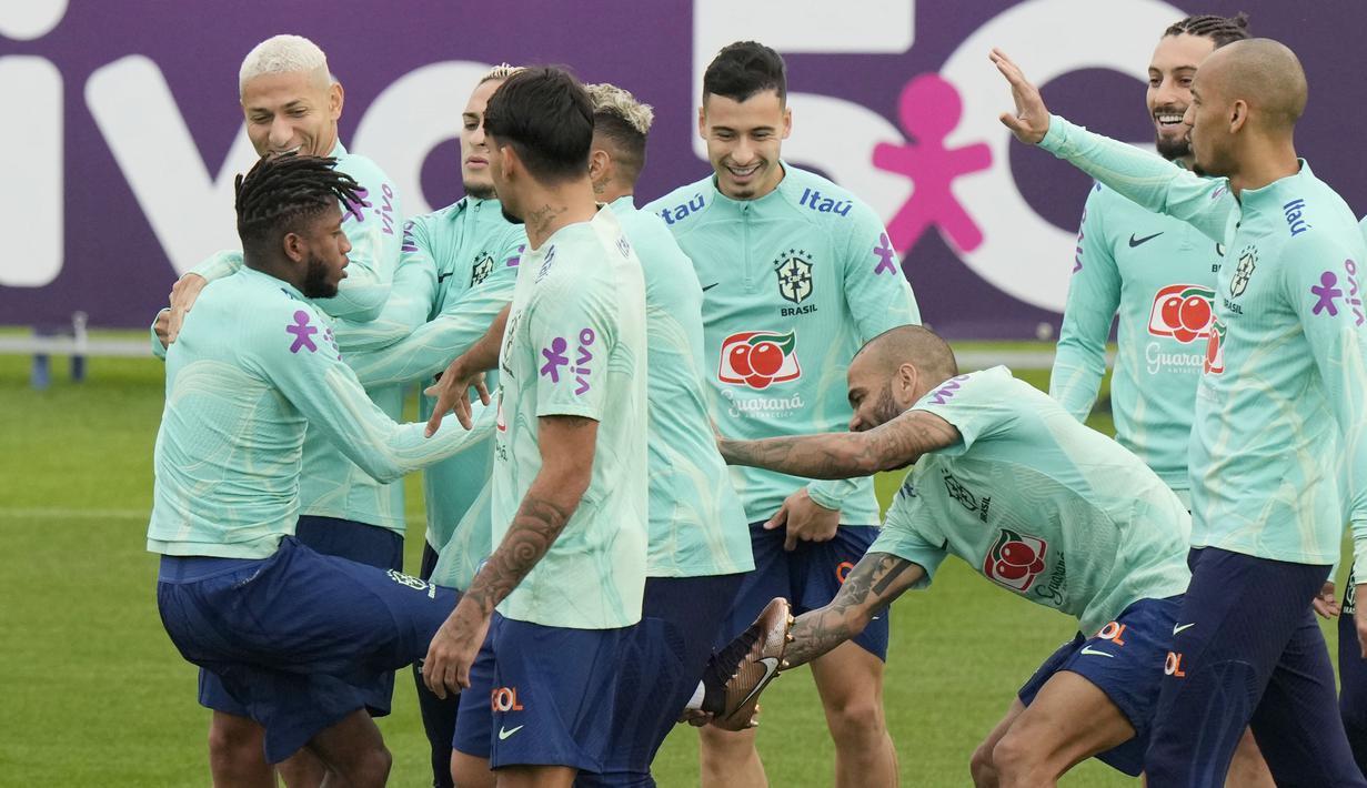 Sebagai pemain yang paling tua di tim, Dani Alves justru menjadi pemain yang paling usil dengan melepas sepatu Fred. Kejadian tersebut spontan membuat rekan-rekan yang berada disekitarnya tertawa. (AP/Luca Bruno)