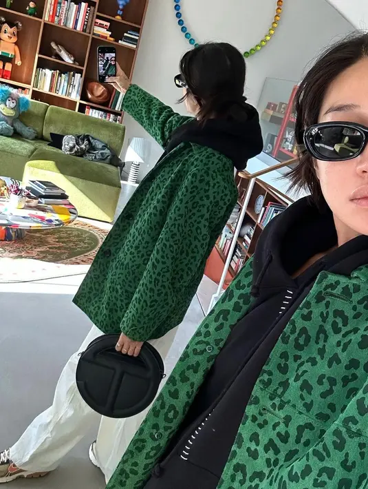 Peggy Gou bermain dengan siluet tumpuk. Ia memilih mengenakan hoodie hitam, ditumpuknya dengan coat bermotif tutul berwarna hijau, dan celana panjang putih. [Foto: Instagram/peggygou_]