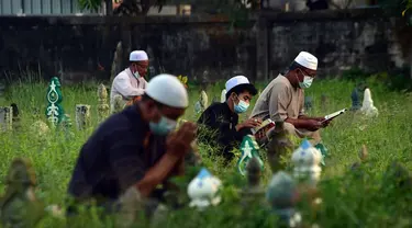 Orang-orang berdoa di sebelah makam kerabat saat perayaan Hari Raya Idul Adha di sebuah pemakaman di Provinsi Narathiwat, Thailand, Rabu (21/7/2021). Setiap Idul Adha atau hari besar Islam lainnya, sebagian warga banyak mendatangi kuburan untuk mendoakan keluarganya. (Madaree TOHLALA/AFP)