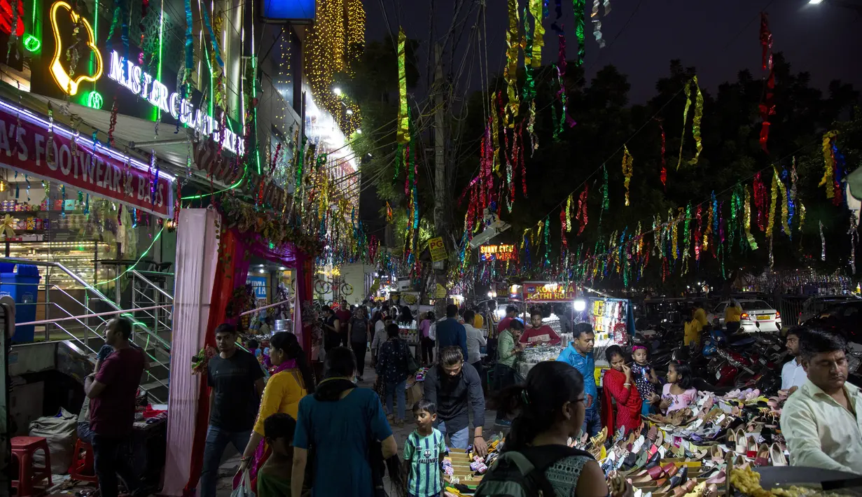 Seorang anak laki-laki berdiri dan melihat orang-orang berbelanja barang-barang dekoratif, lampu tanah liat, dan lampu listrik untuk menghias rumah mereka menjelang festival Diwali di New Delhi, India, Kamis, 20 Oktober 2022. Diwali, festival lampu, akan dirayakan pada 24 Oktober. (AP Photo/Bhumika Saraswati)