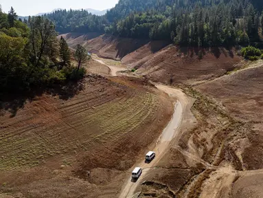 Kendaraan melintasi jalan tanah yang dulunya berada di bawah air di dekat area Bailey Cove di Danau Shasta di Lakehead, California pada (16/10/ 2022). Danau Shasta saat ini memiliki kapasitas air yang menyusut hingga 32% karena kondisi kekeringan yang terus berlanjut di seluruh barat. (JOSH EDELSON / AFP)