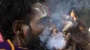 Seorang Sadhu atau orang suci Hindu menghisap ganja menggunakan 'chillum', pipa tanah liat tradisional, menjelang festival Hindu 'Maha Shivaratri', di Kathmandu (9/3/2021). Festival ini juga menandai hari penyempurnaan pernikahan Siwa. (AFP/Prakash Mathema)