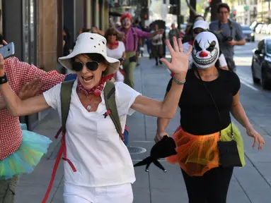 Para peserta berdandan seperti badut mengejar pejalan kaki selama 'Running of the Clowns' di Pasadena, California pada 21 Oktober 2018. Lari dikejar kawanan badut ini merupakan parodi yang mengolok-olok lomba dikejar banteng di Spanyol. (Mark RALSTON/AFP)
