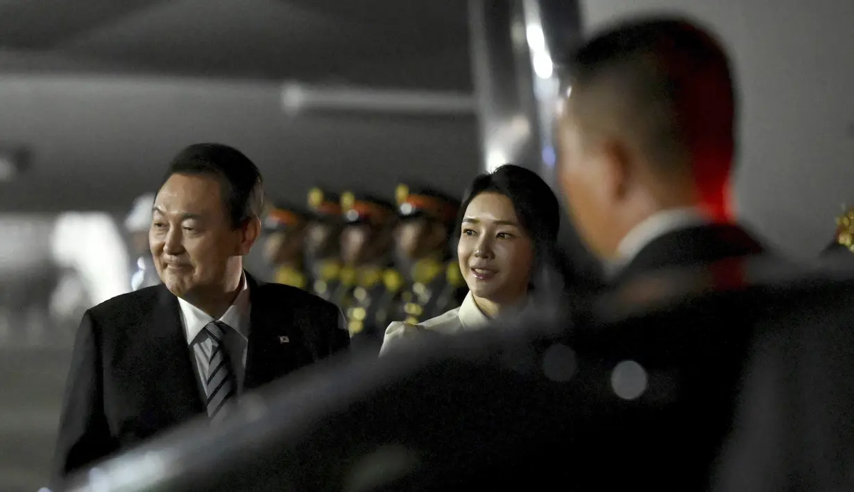 Presiden Korea Selatan Yoon Suk Yeol dan istrinya Kim Keon-hee tiba di Bandara Internasional Ngurah Rai di Bali, Minggu, 13 November 2022. Istri dari Presiden Korsel ini membuat netizen gagal fokus karena parasnya bak artis K-pop. Kecantikannya membuat netizen bertanya-tanya. "Itu ibu negara apa artis kpop sih? Cantik bgt," tutur akun @tya_sastria. (Sonny Tumbelaka/Pool Photo via AP)