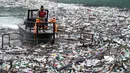 Sebuah perahu mendorong berton-ton sampah yang tersangkut di danau penimbunan Potpecko dekat Priboj, di barat daya Serbia, Kamis (12/1/2023). Serbia dan negara-negara Balkan lainnya kewalahan oleh sampah komunal setelah beberapa dekade diabaikan dan kurangnya kebijakan pengelolaan limbah yang efisien di negara-negara yang bercita-cita untuk bergabung dengan Uni Eropa. (AP Photo/Marjan Vucetic)