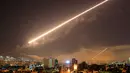 Langit ibu kota Damaskus terang menyala menyusul serangan udara koalisi negara Barat di Suriah, Sabtu (14/4). Presiden AS Donald Trump memerintahkan serangan rudal di Suriah sebagai pembalasan atas dugaan serangan kimia di negeri itu. (AP/Hassan Ammar)