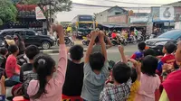 Sejumlah anak berjoget sambil merekam fenomena klakson bus telolet yang kembali marak di Jalan Raya Ciledug, Tangerang, Minggu (18/6/2023). (Liputan6.com/Angga Yuniar)