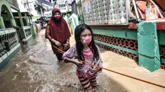 Seorang anak dan wanita berpegangan pada tali saat menyusuri banjir yang merendam permukiman di Kebon Pala, Jakarta, Senin (8/2/2021). Hujan deras yang mengguyur Ibu Kota dan Bogor menyebabkan permukiman di Kebon Pala terendam banjir sejak Minggu (7/2/2021) sore. (merdeka.com/Iqbal S. Nugroho)
