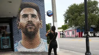 Jessica Ospina mengambil foto mural Lionel Messi di luar restoran Fiorito, di Miami, Amerika Serikat, Rabu, 7 Juni 2023. (AP Photo/Lynne Sladky)