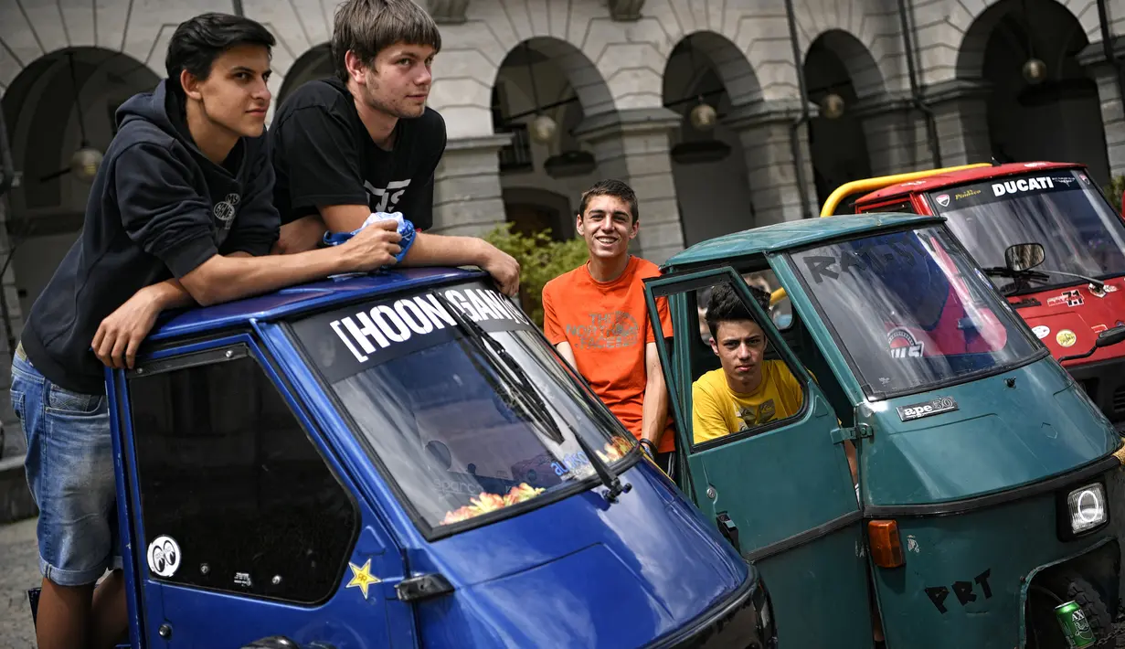 Sejumlah pria mengikuti pameran memperingati 70 tahun Ape di Aosta, Italia utara (1/7). Alat transportasi mirip Bajaj ini bisa digunakan sebagai kendaraan penumpang atau moda pengangkut perniagaan. (AFP Photo/Marco Bertorello)
