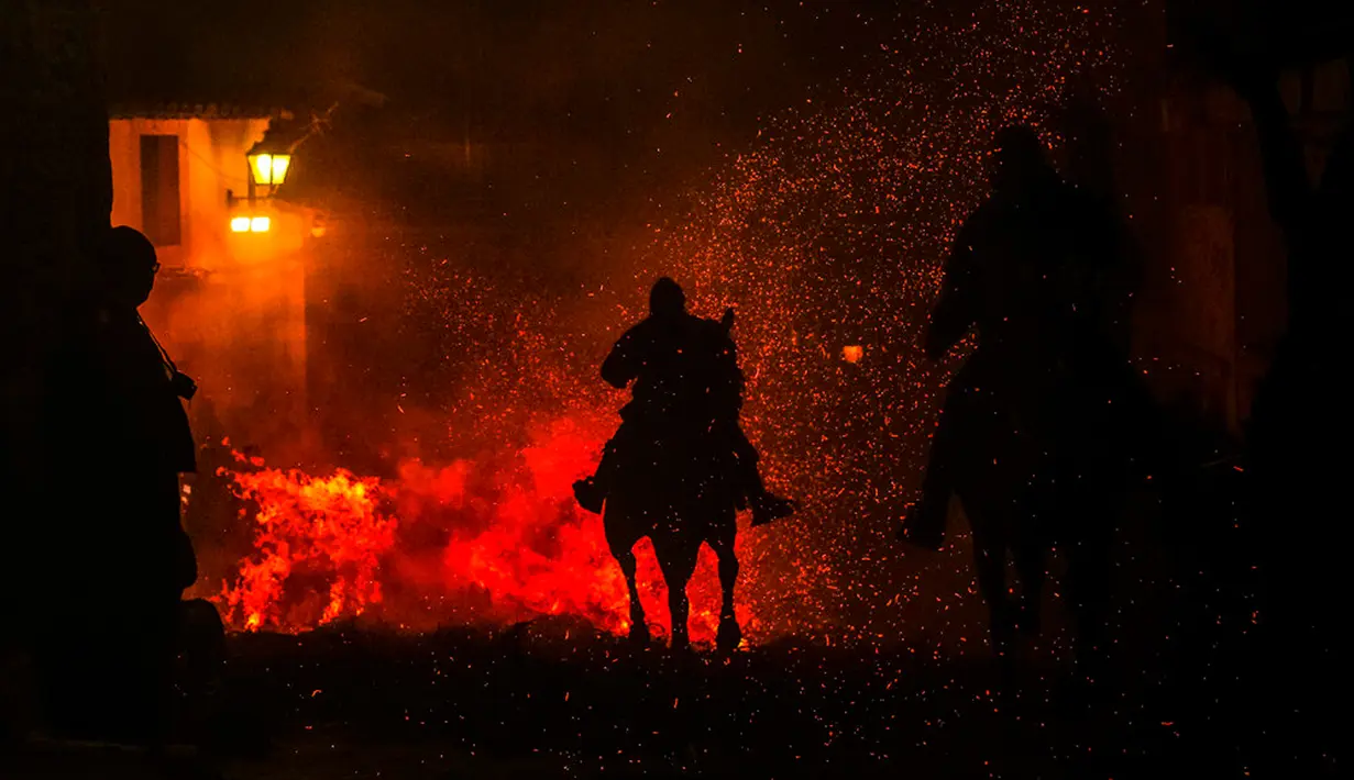 Seorang pria menunggang kuda melintasi kobaran api dalam tradisi tahunan Luminarias memperingati Hari Santo Anthony (santo pelindung hewan) di San Bartolome de Pinares, Spanyol, 16 Januari 2023. Tradisi yang sudah berlangsung selama 500 tahun ini dilakukan sebagai upaya 'pemurnian' hewan dengan cara melintasi kobaran api. (AP Photo/Manu Fernandez)