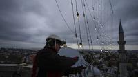 Mahya master Cemil Buyurkan bekerja dalam pemasangan pesan lampu di puncak salah satu menara Masjid Suleymaniye di Istanbul, Turki, Rabu, 6 Maret 2024. (AP Photo/Emrah Gurel)