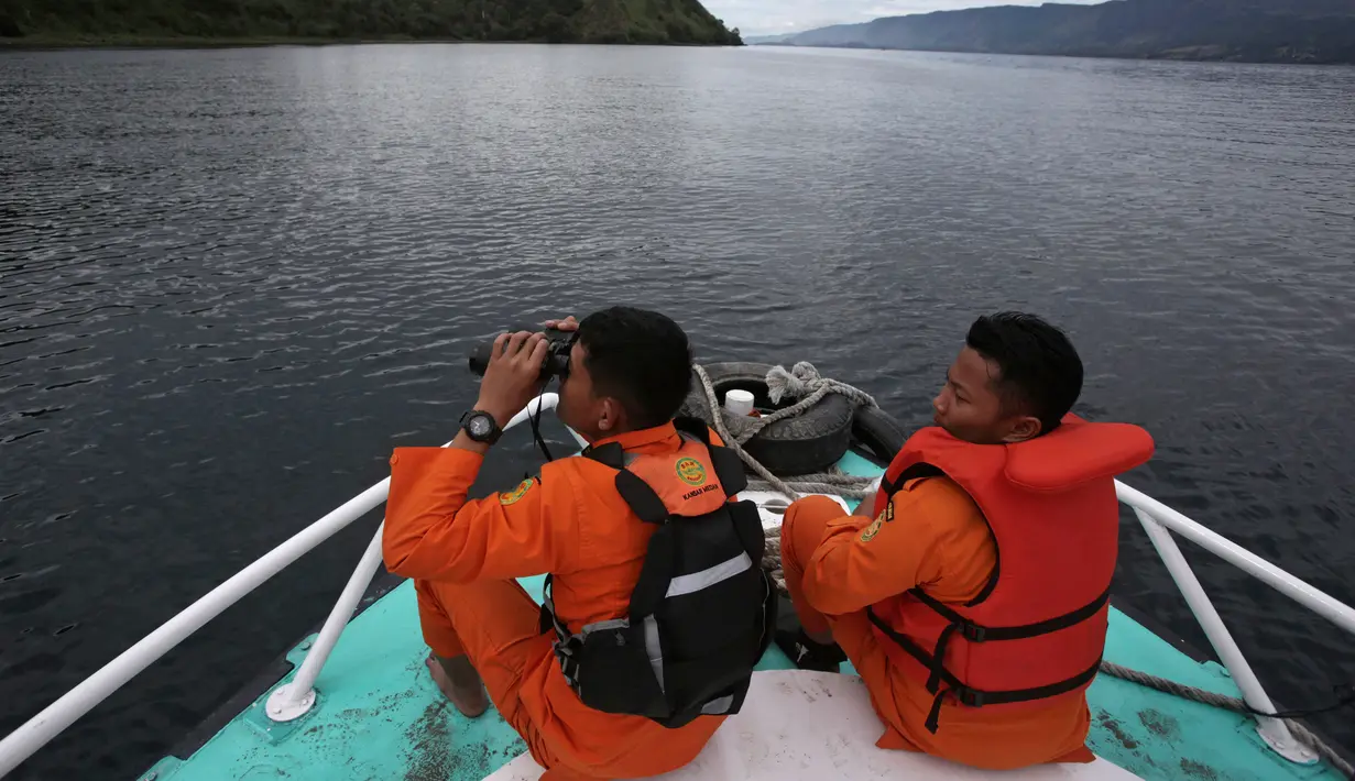 Tim SAR menggunakan teropong saat proses pencarian korban KM Sinar Bangun di Danau Toba, Sumatra Utara, Rabu (20/6). Sebelumnya, KM Sinar Bangun yang mengangkut 128 penumpang tenggelam di Danau Toba pada Senin (18/6) sore. (AP/Binsar Bakkara)