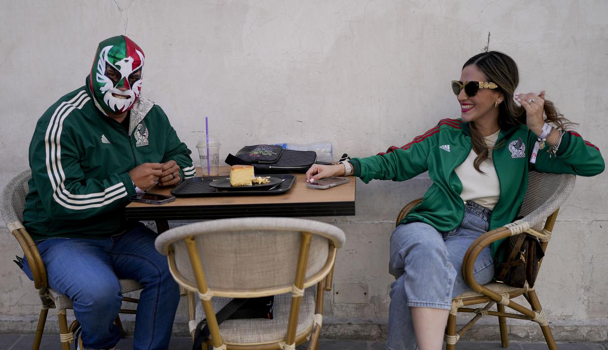 Dua pendukung Meksiko menunggu di restoran untuk laga Grup C antara Meksiko melawan Polandia di Doha, Senin (21/11/2022). (AP/Natacha Pisarenko)