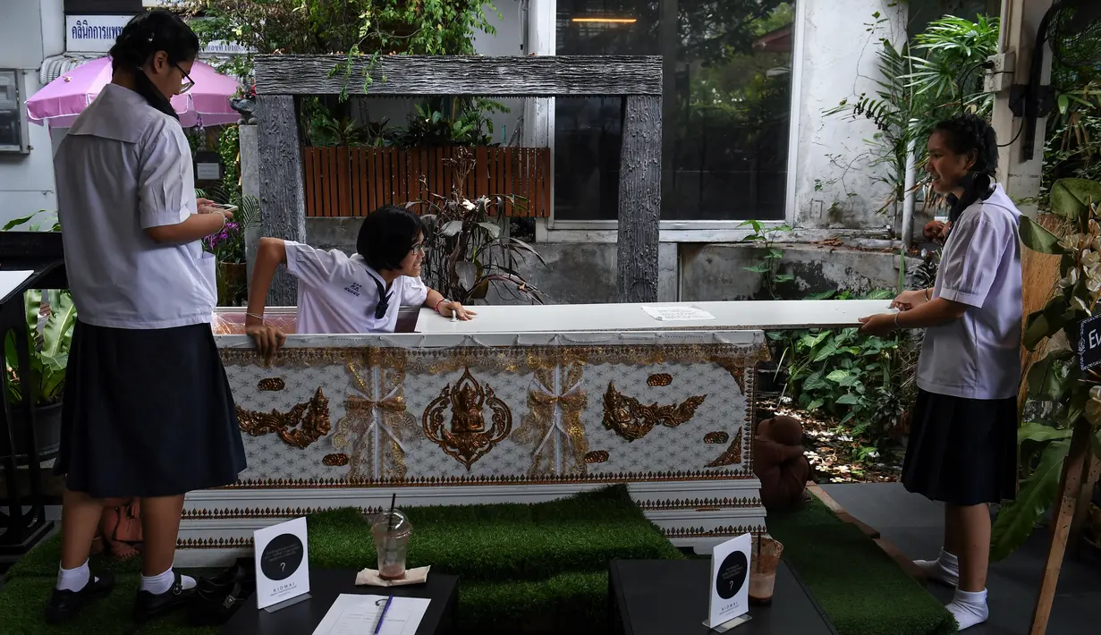Seorang siswa remaja mencoba masuk ke dalam peti mati di Kid Mai Death Awareness Cafe, Thailand (30/3). Selain itu cafe ini juga menyediakan menu yang cukup aneh seperti minuman rasa "kematian" dan "menyakitkan". (AFP/Lillian Suwanrumpha)