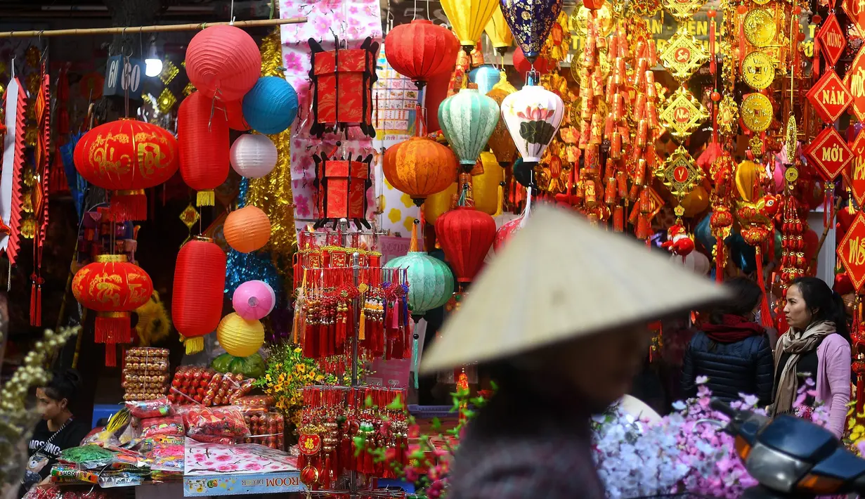 Wanita Vietnam melihat-lihat dekorasi Tahun Baru Imlek atau perayaan Tet di sebuah pasar pusat Kota Tua Hanoi, Senin (28/1). Di Vietnam, tahun baru imlek dikenal dengan nama Tet Nguyen Dan atau lebih akrab disingkat sebagai Tet. (Manan VATSYAYANA/AFP)