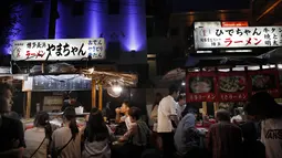 Orang-orang menikmati makan malam di stand makanan terbuka (Yatai) di Fukuoka, Jepang barat daya (30/9/2019). Yatai menyediakan lingkungan luar ruangan yang nyaman untuk menikmati berbagai makanan yang umumnya sederhana dan mengenyangkan. (AP Photo/Christophe Ena)